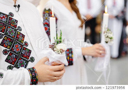 Couple wearing traditional Romanian costume holding candles during a religious ceremony Couple wearing traditional Romanian costume holding candles during a religious ceremony 121973956