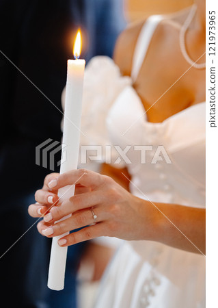 Bride holding burning candle during wedding ceremony 121973965