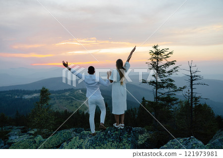 Couple Wearing White Clothes Raising Arms at Mountain Summit During Sunset Couple Wearing White Clothes Raising Arms at Mountain Summit During Sunset 121973981