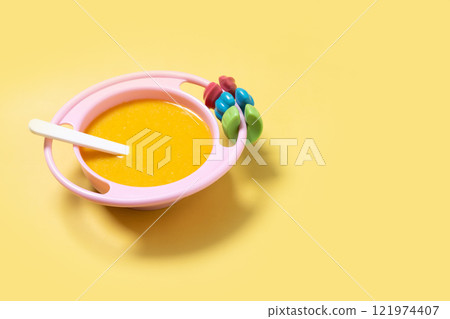 Bowl with baby food. vegetable puree on yellow background 121974407