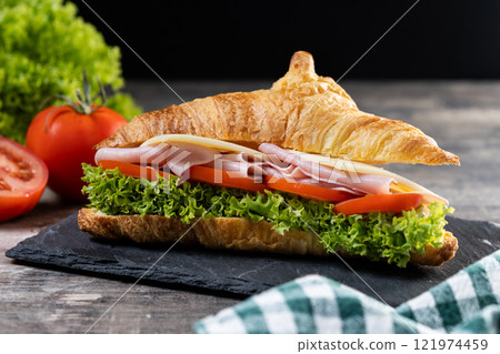 Croissant with ham, cheese and vegetables on wooden table 121974459