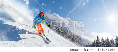 A skier skiing downhill a groomed alpine slope during sunny winter day A skier skiing downhill a groomed alpine slope during sunny winter day 121974568