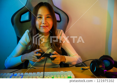 Gamer using joystick controller for virtual tournament plays online video game with computer neon lights, woman wear gaming headphones playing live stream esports games console at home, Esport concept Gamer using joystick controller for virtual tournament plays online video game with computer neon lights, woman wear gaming headphones playing live stream esports games console at home, Esport concept 121975102