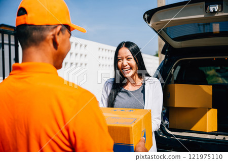 Modern home delivery depicted as a courier in uniform delivers a cardboard parcel to a smiling woman at her house emphasizing efficient delivery service and customer happiness. Modern home delivery depicted as a courier in uniform delivers a cardboard parcel to a smiling woman at her house emphasizing efficient delivery service and customer happiness. 121975110