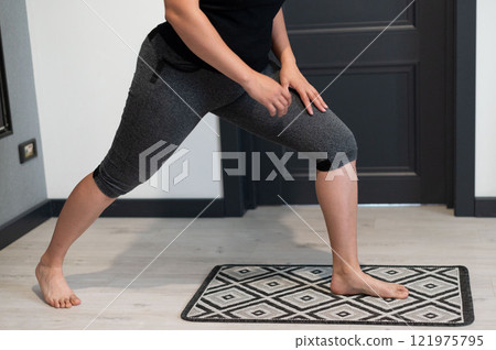 Woman stretching leg at home, fitness routine. Great for health and wellness content. 121975795