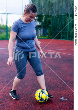 Woman practicing soccer on a court. Focused on ball control and technique. Woman practicing soccer on a court. Focused on ball control and technique. 121975840