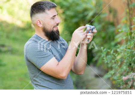 Man gently holds a small bird outdoors, enjoying a peaceful moment in nature. 121975851