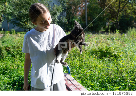 Girl holding a fluffy rabbit in a park. A sunny day outdoors. 121975892
