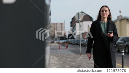 Woman receiving parcel from post terminal machine using smartphone outdoors. Parcel delivery machine. Mail delivery and post service, online shopping, e commerce concept. Woman receiving parcel from post terminal machine using smartphone outdoors. Parcel delivery machine. Mail delivery and post service, online shopping, e commerce concept. 121978078