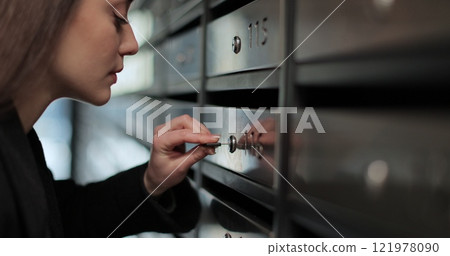 Close up beautiful woman unlocking mailbox and taking mail in apartment building. Close up beautiful woman unlocking mailbox and taking mail in apartment building. 121978090