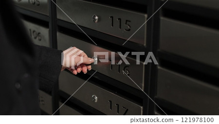 Close-up woman is opening her mailbox inside a cluster of mailboxes for her apartment. Mail shipping concept. 121978100