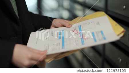 Close up woman is opening her mailbox inside a cluster of mailboxes for her apartment. Payment notification letter. Mail shipping concept. 121978103