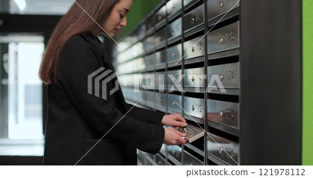 Woman opening postbox and taking mail for her apartment. Mail shipping concept. Woman opening postbox and taking mail for her apartment. Mail shipping concept. 121978112