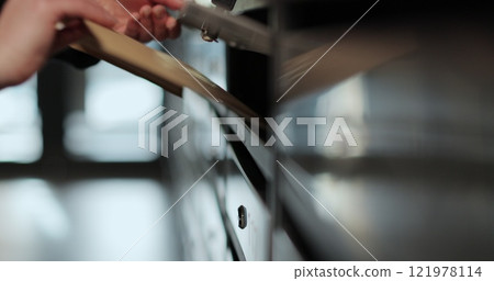 Close-up woman is opening her mailbox inside a cluster of mailboxes for her apartment. Mail shipping concept. 121978114