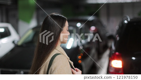 Young woman walks through the parking lot of shopping center to car. Puts paper bags with purchases. Shopping, sale, discounts in stores. 121978150