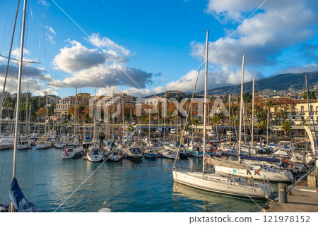 A stunning view of a Funchal marina on Madeira island filled with boats, yachts and sailboats under a beautiful sunset in a lively coastal city 121978152