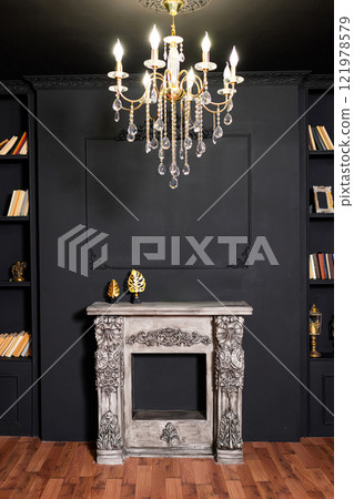 plaster fake fireplace on the background of a black wall. classic photo zone with a fireplace plaster fake fireplace on the background of a black wall. classic photo zone with a fireplace 121978579
