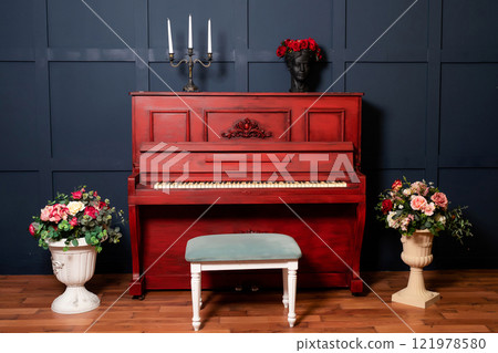 red piano against dark blue wall with candles. photo zone with piano in photo studio 121978580