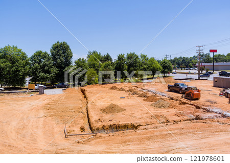 Heavy machinery is shaping land in trenches for foundation at construction site under works area Heavy machinery is shaping land in trenches for foundation at construction site under works area 121978601