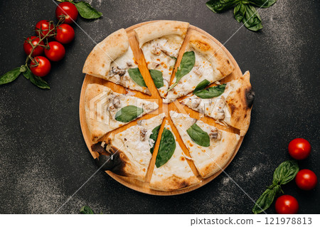 Wood-fired white pizza slices with mushrooms, spinach, and creamy cheese on a rustic wooden plate 121978813