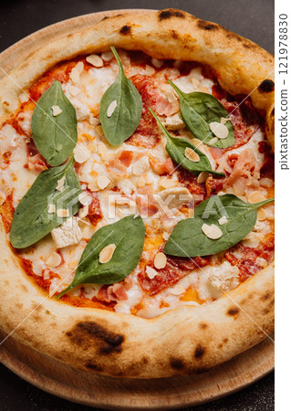 Delicious Italian pizza with fresh spinach, almonds, and cheese on a wooden board 121978830