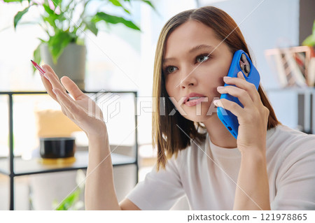 Headshot portrait of young serious woman talking on mobile phone in coworking Headshot portrait of young serious woman talking on mobile phone in coworking 121978865