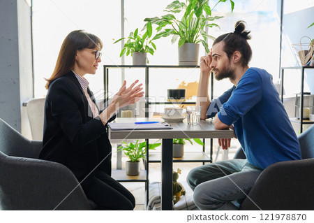 Middle aged female mental health specialist, insurance agent working with young male 121978870