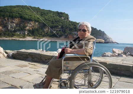 Elderly woman in a wheelchair on the sea 121979018