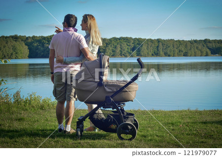Young couple walking with newborn baby in stroller on lake Young couple walking with newborn baby in stroller on lake 121979077