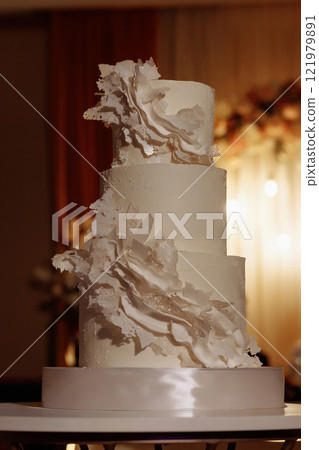 A three tier wedding cake with white frosting and white flowers A three tier wedding cake with white frosting and white flowers 121979891