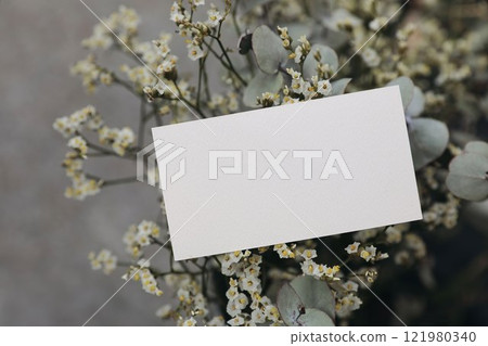 Floral wedding, birthday mockup. Blank textured paper business card, invitation. White limonium flowers and eucalyptus tree branches bouquet. Blurred background. Floristry concept. Gift note. 121980340