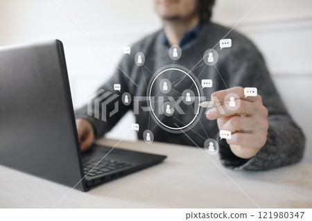 Man in grey sweater with laptop using modern interface with white icons. Social network connection. Chatting, partnership and friendship concept. User interface. Modern communication technology Man in grey sweater with laptop using modern interface with white icons. Social network connection. Chatting, partnership and friendship concept. User interface. Modern communication technology 121980347