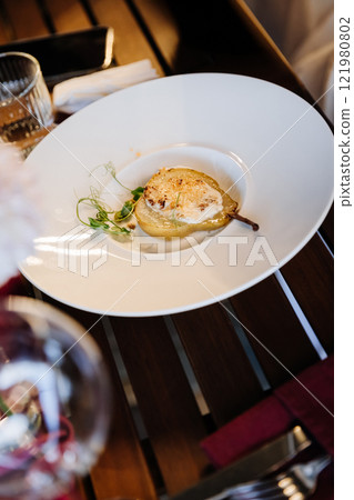 Gourmet poached pear dessert served on an elegant dining table with chic decor and fine wine 121980802
