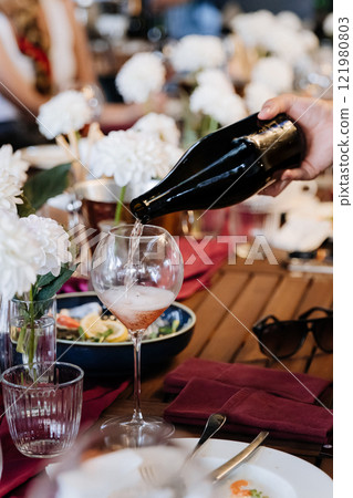 Elegant wine pouring at a beautifully set table, perfect for celebrations and fine dining moments Elegant wine pouring at a beautifully set table, perfect for celebrations and fine dining moments 121980803