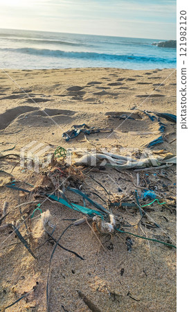 Garbage, plastic, and wastes on the beach of Portugal. Sand beaches polluted with pieces of plastic, cigarette pack 121982120