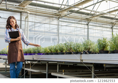 Glasshouse supervisor checking the plants and making notes 121982553