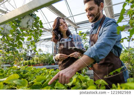 Greenhouse worker talking to a supervisor and looking involved 121982569
