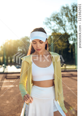 Pretty young tennis player with a racket at the tennis court 121982601