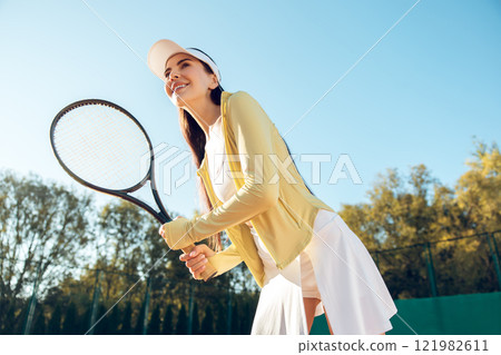 Young long-haired woman in white cap playing tennis Young long-haired woman in white cap playing tennis 121982611