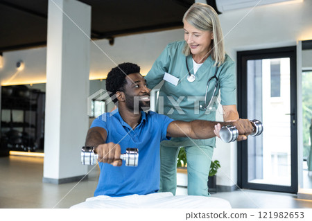African american young man working on his arms , female doctor guiding him African american young man working on his arms , female doctor guiding him 121982653