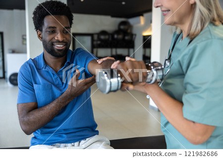 Female doctor guiding a young male patient in physical therapy 121982686