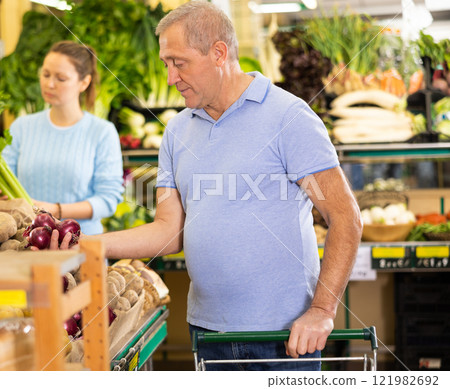 Busy casual elderly man buying local red onions during shopping in hypermarket 121982692