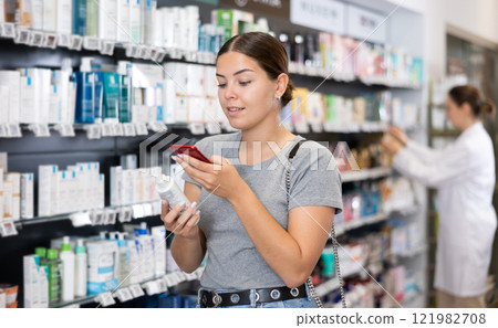 In pharmacy visitor scan QR Code and reads composition of cream for problematic skin. In pharmacy visitor scan QR Code and reads composition of cream for problematic skin. 121982708