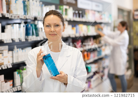 In pharmacy, female specialist holds and shows new effective remedy for moisturizing delicate skin In pharmacy, female specialist holds and shows new effective remedy for moisturizing delicate skin 121982715