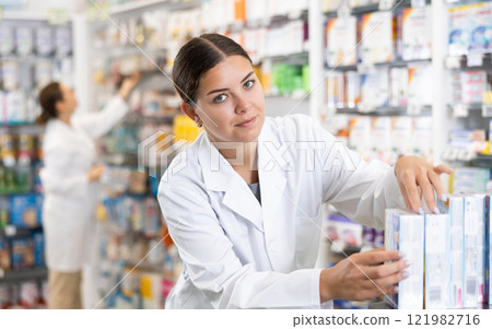In pharmacy, woman chemist makes out showcase with warming analgesic ointments 121982716