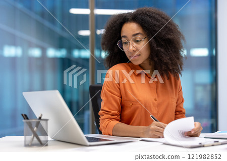 Serious focused woman doing paperwork inside office. Accountant financier signing contracts and filling out tax forms. Businesswoman with documents and graphs reports. Serious focused woman doing paperwork inside office. Accountant financier signing contracts and filling out tax forms. Businesswoman with documents and graphs reports. 121982852