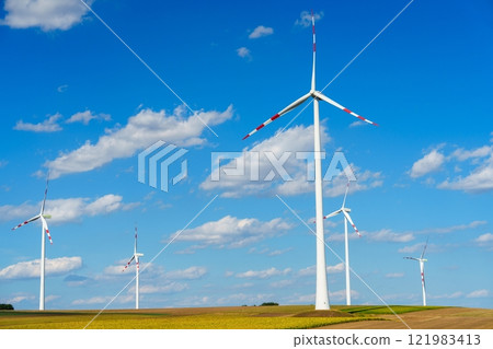 Wind turbines generating clean energy in a rural field under a blue sky with white clouds Wind turbines generating clean energy in a rural field under a blue sky with white clouds 121983413