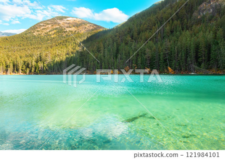 Mountain lake with emerald waters surrounded with forests in fall. 121984101