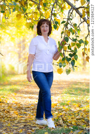 Senior woman in casual clothes in the yellow autumn park. 121984127