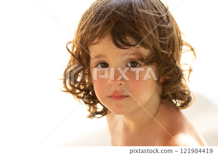 Close-up portrait of a cute toddler girl on the sunny beach. Close-up portrait of a cute toddler girl on the sunny beach. 121984419